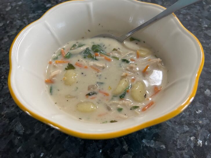 serving of chicken and gnocchi soup in bowl with spoon