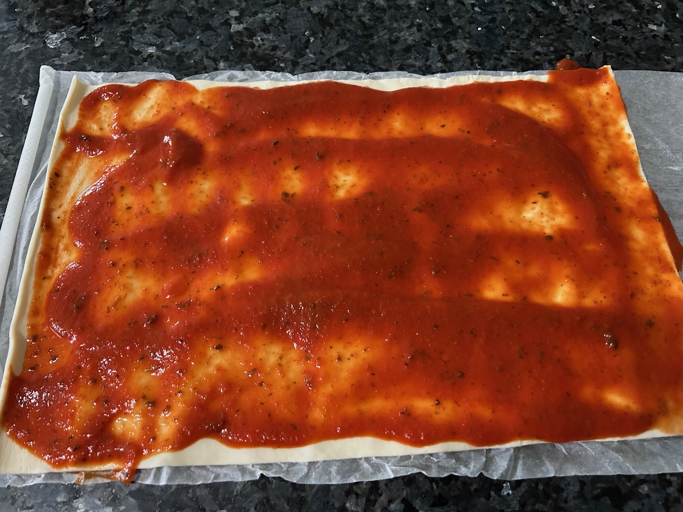 pizza sauce spread over puff pastry