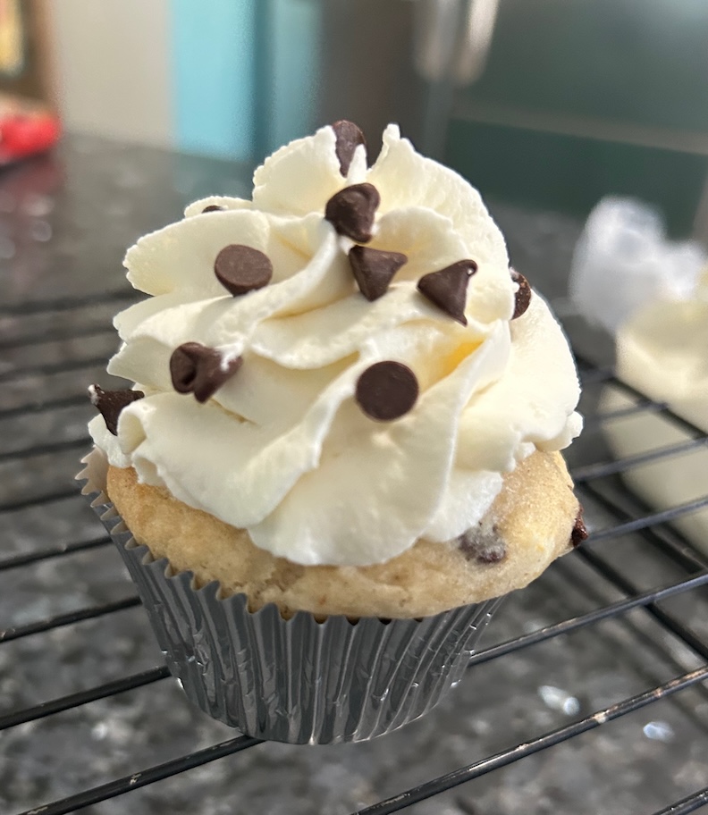 cupcake frosted with white swirls and chocolate chips