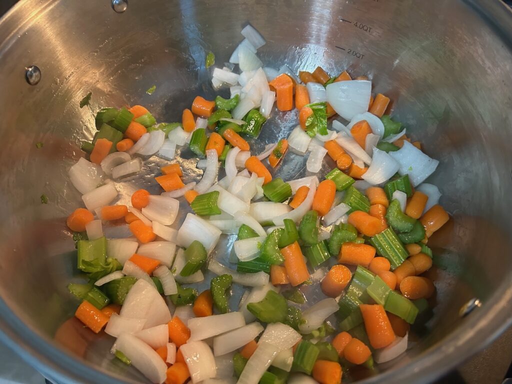 cut veggies in pot on stove: carrots, onions, celery